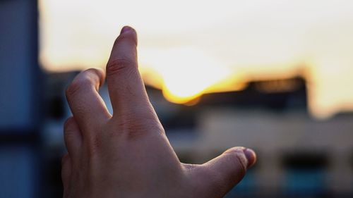 Close-up of human hand against sky