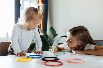 Girl with sister drawing on paper at home