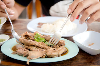 Midsection of man eating food at table