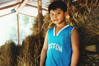 Portrait of boy standing against hay