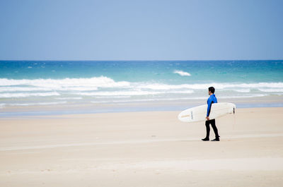 Man standing with surfboard at beach