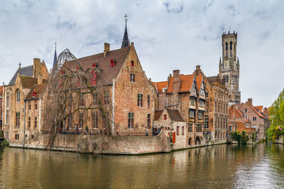 Buildings by river against sky in city