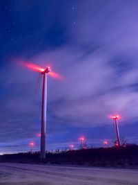 Low angle view of windmills against blue sky at night