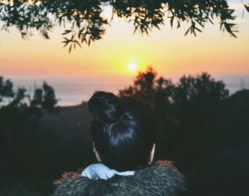Rear view of woman looking at sunset over sea