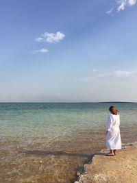 Rear view of woman looking at sea against sky