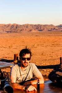 Portrait of man sitting against landscape and sky