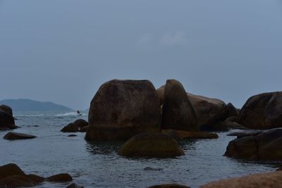 Rocks by sea against clear sky