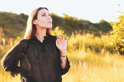 Young woman standing against lake during sunset