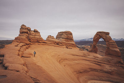 A man with a child is standing near delicate arch at arches np