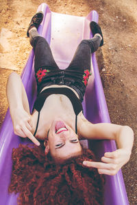 High angle portrait of young woman showing obscene gesture on slide