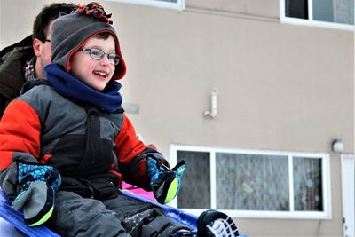 Man tobogganing son on snow during winter