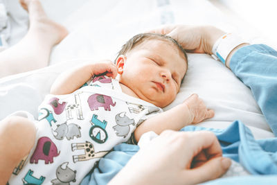 Cute baby sleeping with mother in hospital