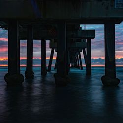 Pier in sea at sunset