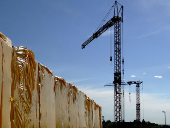 Low angle view of cranes against blue sky