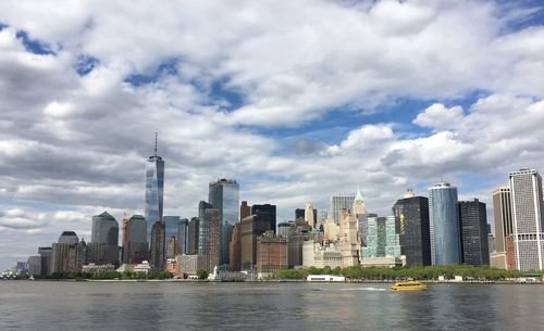 City at waterfront against cloudy sky