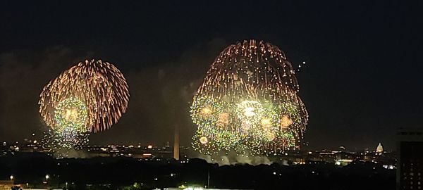 Firework display over illuminated buildings in city at night