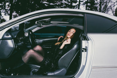 Full length portrait of young woman sitting in car