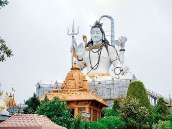 Statue against trees and building against sky