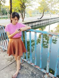 Woman using phone while standing by railing