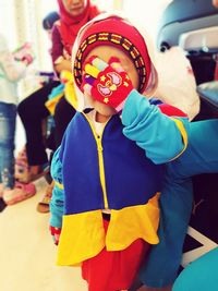 Close-up of boy standing by multi colored umbrella