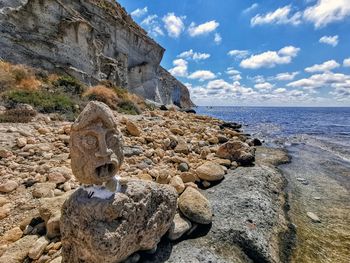 Scenic view of rocks by sea against sky