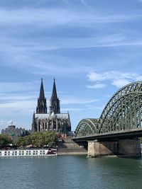 Arch bridge over river by buildings against sky in city