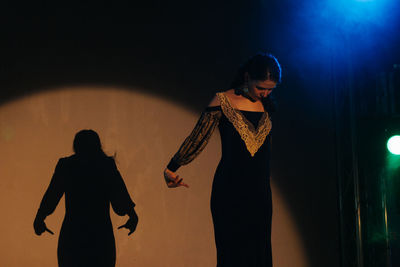 Silhouette couple standing against illuminated light at night