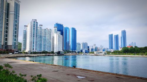 Sea by buildings against sky in city