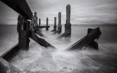 Damaged pier over sea against sky