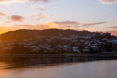 Scenic view of river by city against sky at sunset