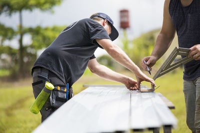 Two men marking measurements on steel excursion for solar panels.