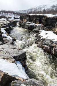 River flowing through snow covered landscape