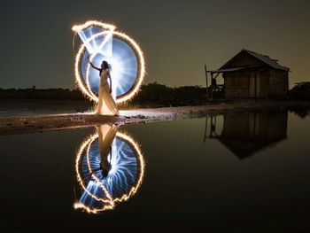 Ferris wheel by lake against sky at night