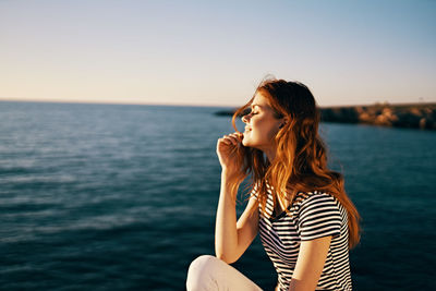 Beautiful young woman in sea against sky