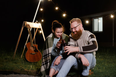 Men sitting in a man holding camera while standing at night