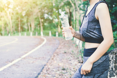 Midsection of woman holding water bottle