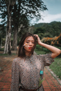 Portrait of young woman standing against tree