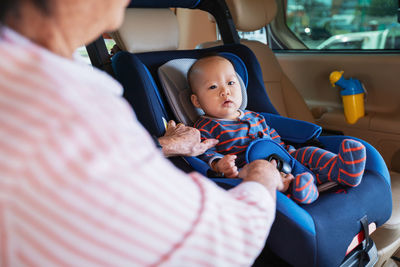 Midsection of grandmother sitting with grandson in car