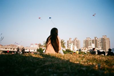 Woman flying against buildings in city against clear sky