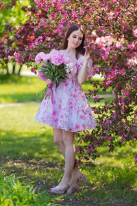 Portrait of young woman standing against plants