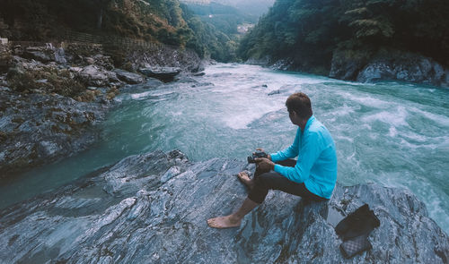 Rear view of man sitting on rock