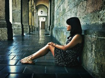 Side view of young woman sitting in corridor of hospicio cabanas