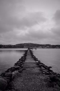 Pier on sea against cloudy sky