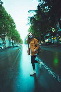 Portrait of young woman walking on road in city