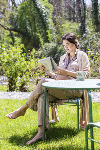 Young woman sitting on book in park