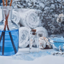 Close-up of rock salt and essential oil with towels on table