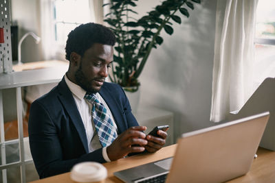 Side view of young man using laptop at office