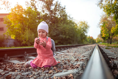 Cute toddler playing with stones on the railroad embankment. dangerous games