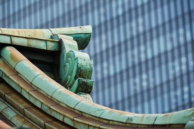 Low angle view of japanese temple roof tiles in front of modern building 