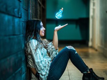 Full length of woman sitting against wall